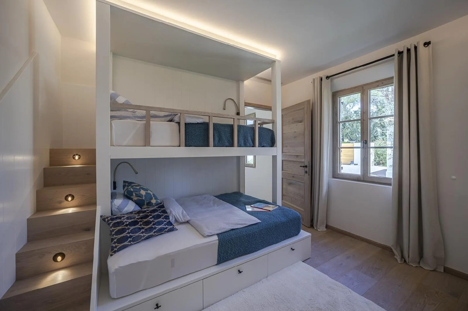 Weißes Einbau-Stockbett mit Holzgeländer, Treppe mit Stufenlicht und Schubladen