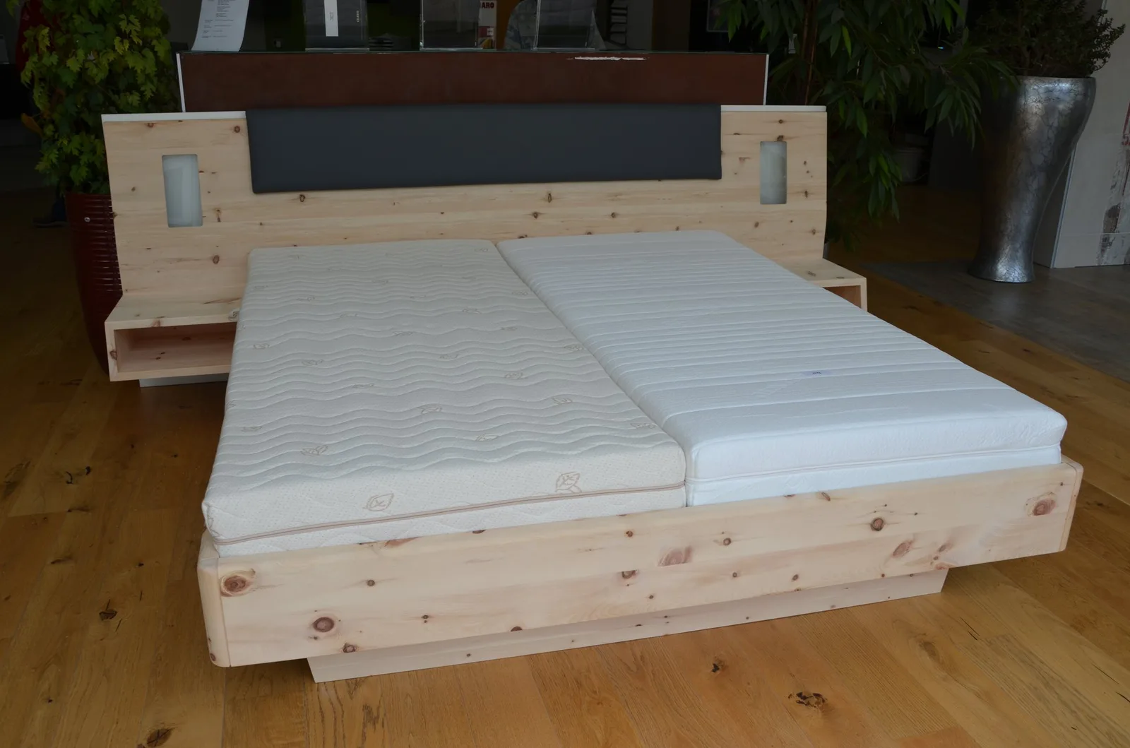 Bett aus hellem Holz mit Kopfteil und Nachtkästchen