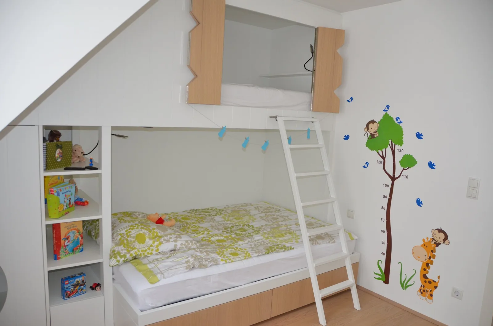 Kinderzimmer mit Hochbett und Leiter unter der Dachschräge, daneben Regal